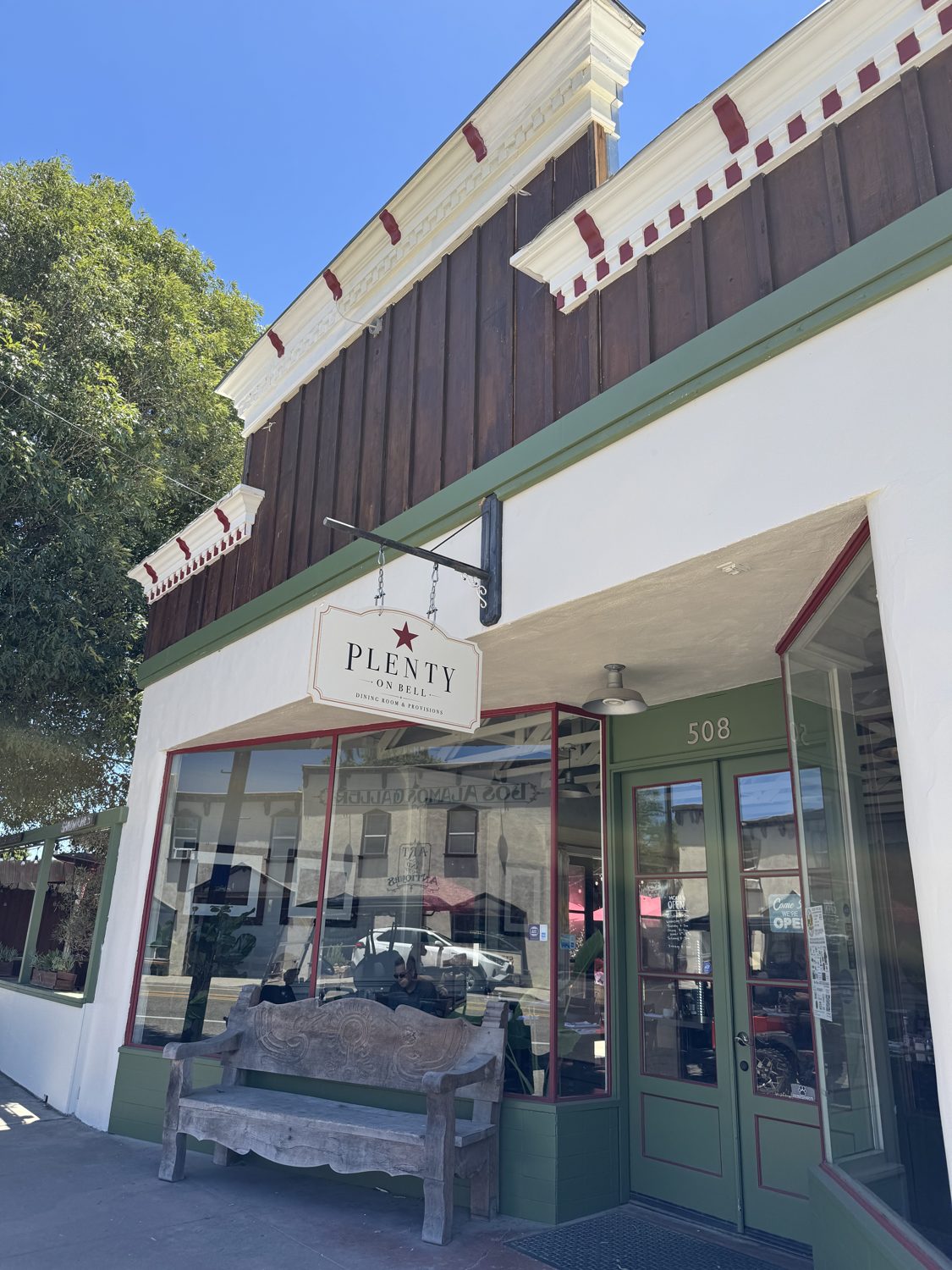 The storefront of Plenty on Bell — green doors and hanging sign at 508 Bell Street, Los Alamos